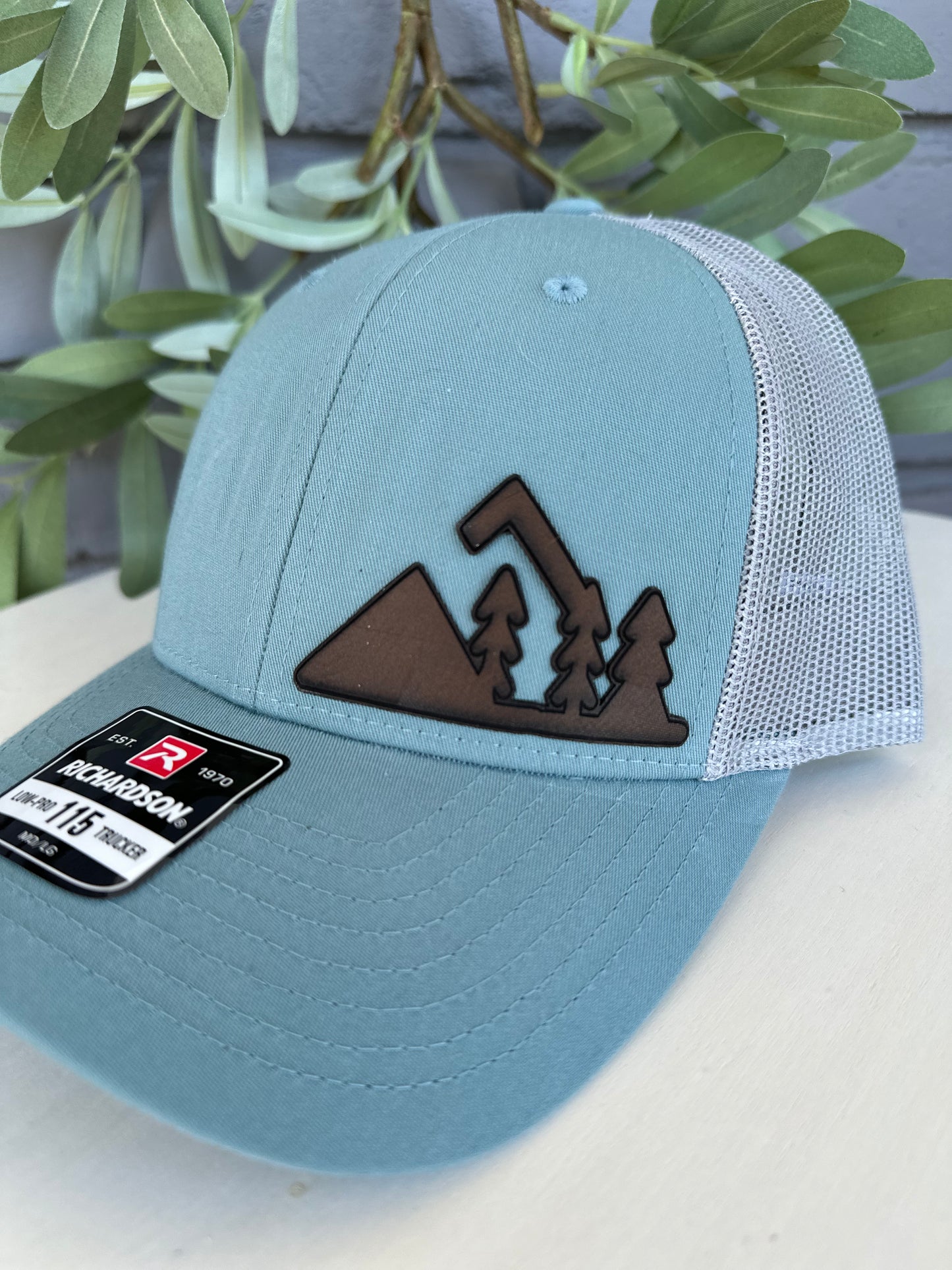 Trucker hat with mountain and trees leather patch