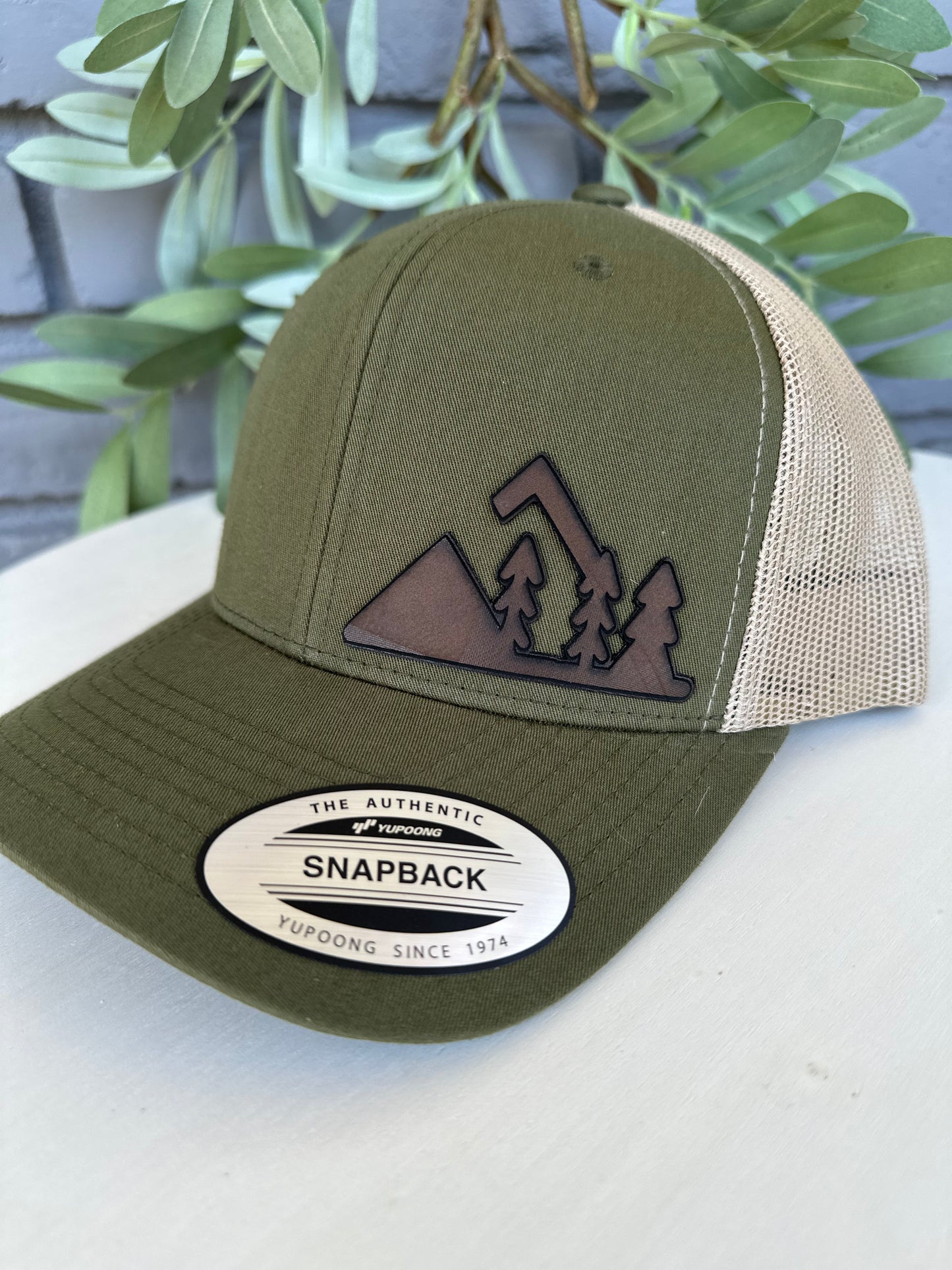 Trucker hat with mountain and trees leather patch