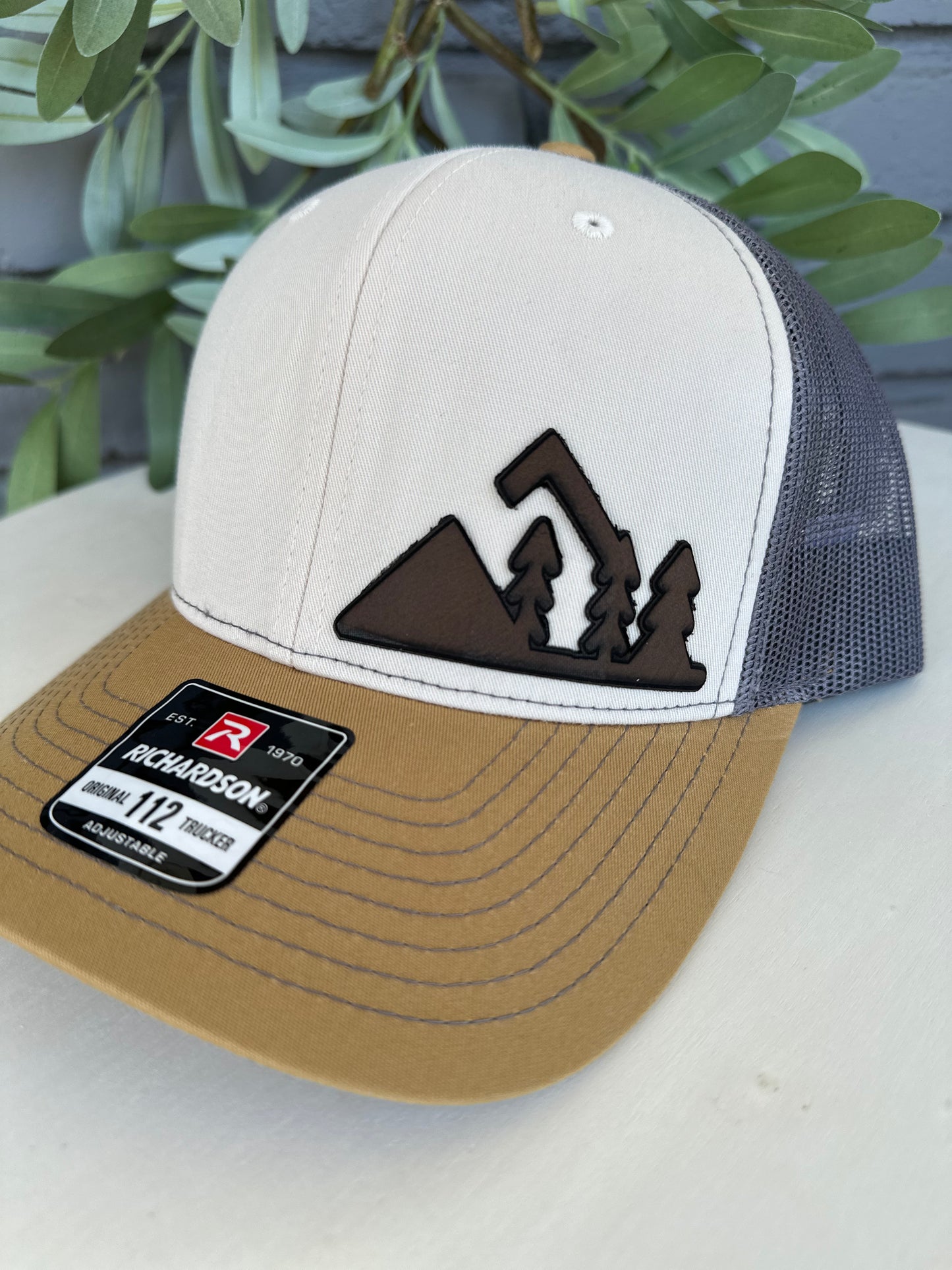 Trucker hat with mountain and trees leather patch