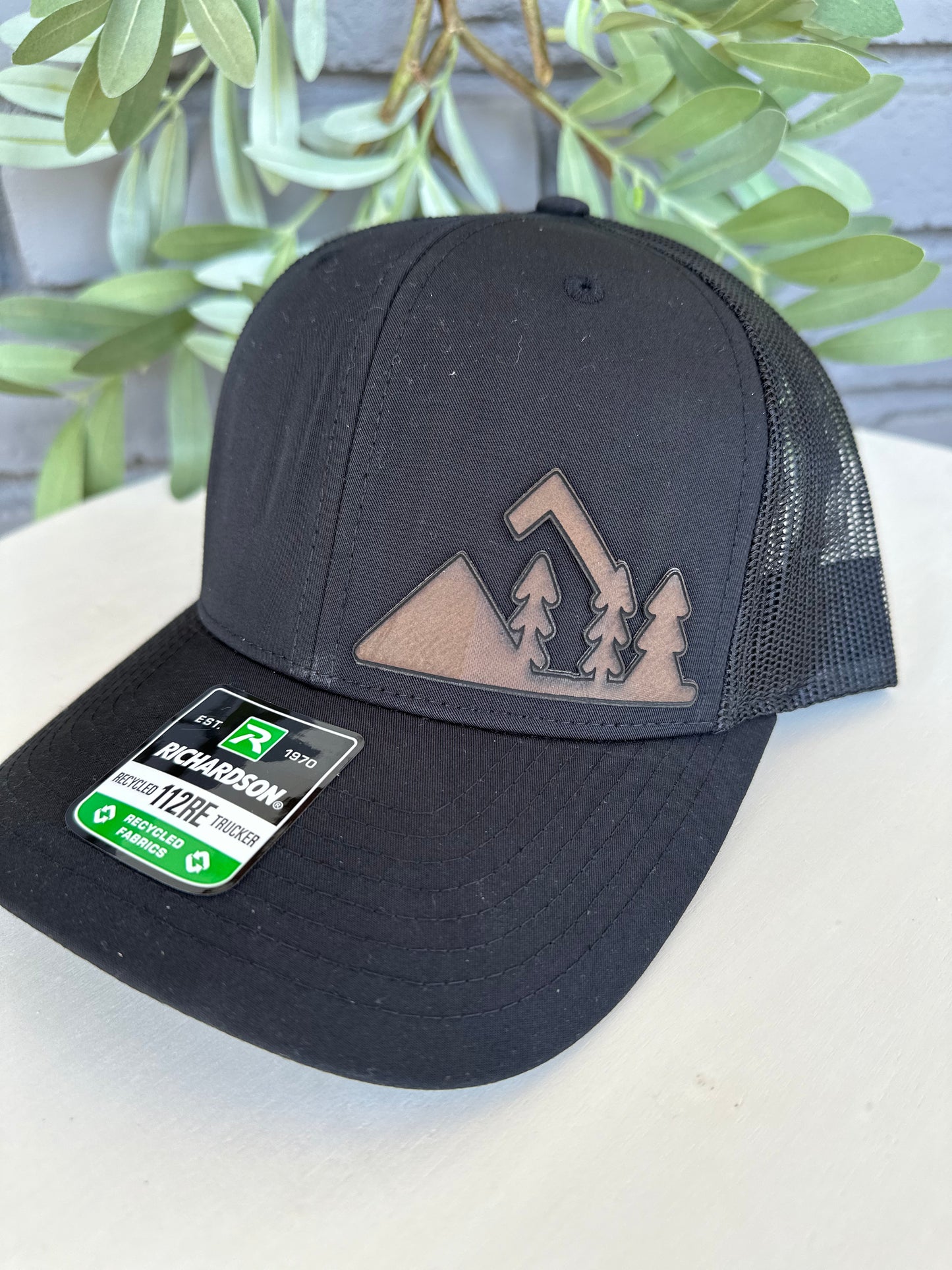 Trucker hat with mountain and trees leather patch