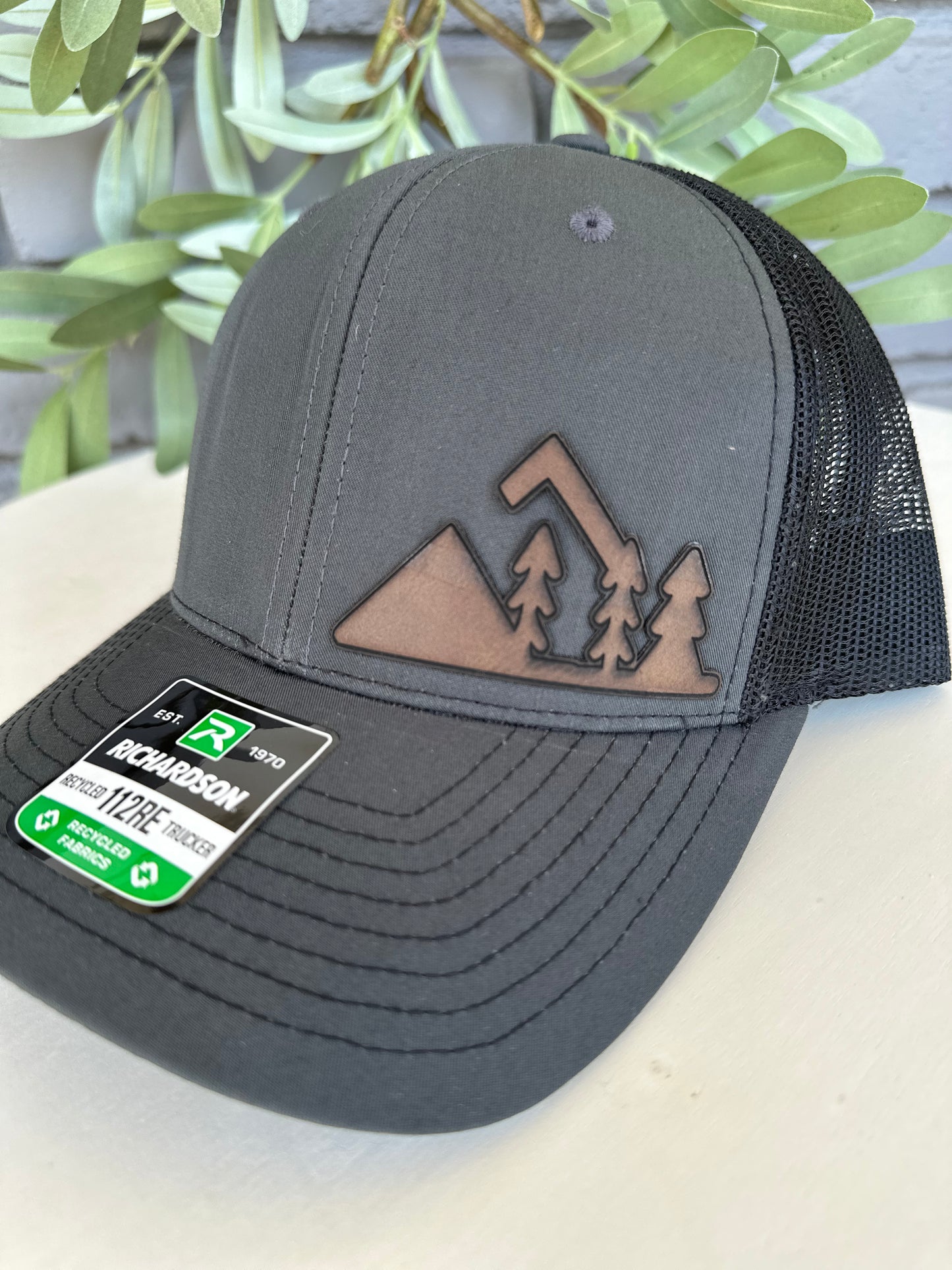 Trucker hat with mountain and trees leather patch