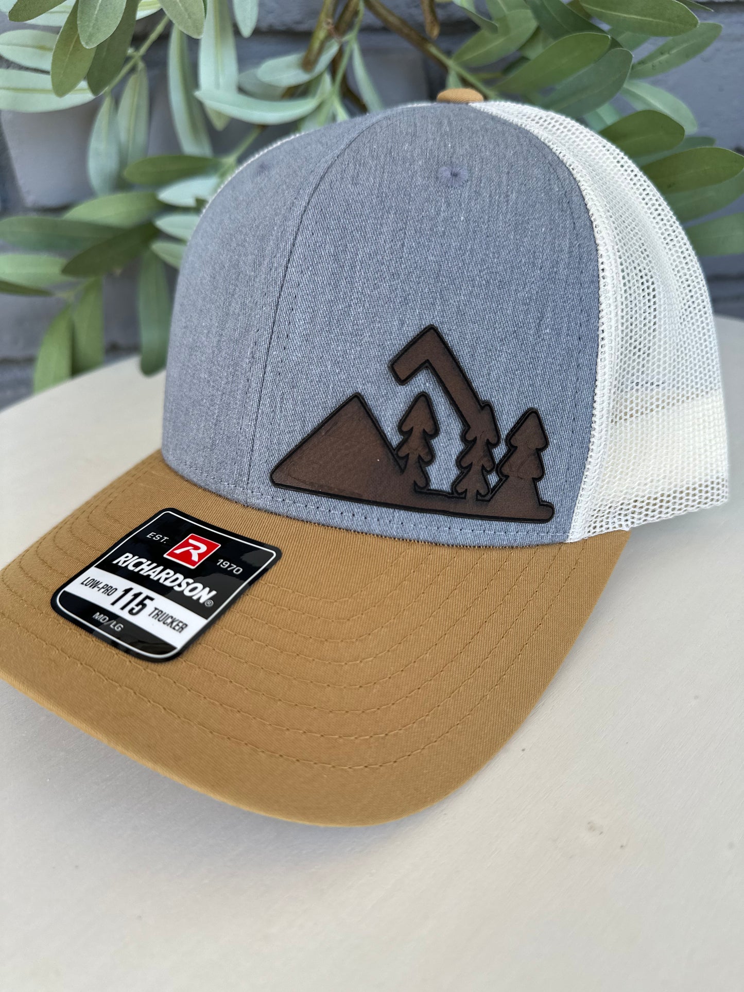 Trucker hat with mountain and trees leather patch